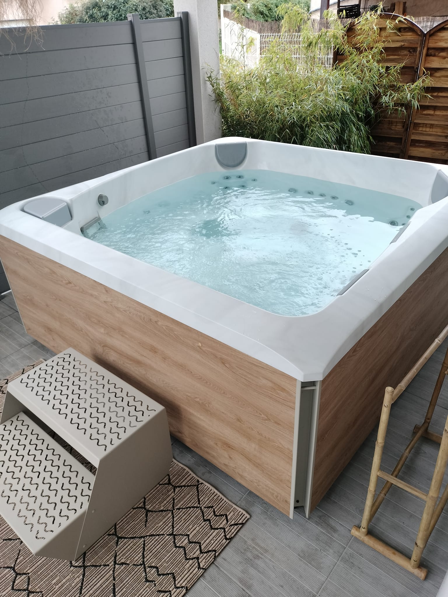 Jacuzzi extérieur moderne sur terrasse zen chez echapetvous à Tarbes, entouré de bambous et déco bois chaleureuse