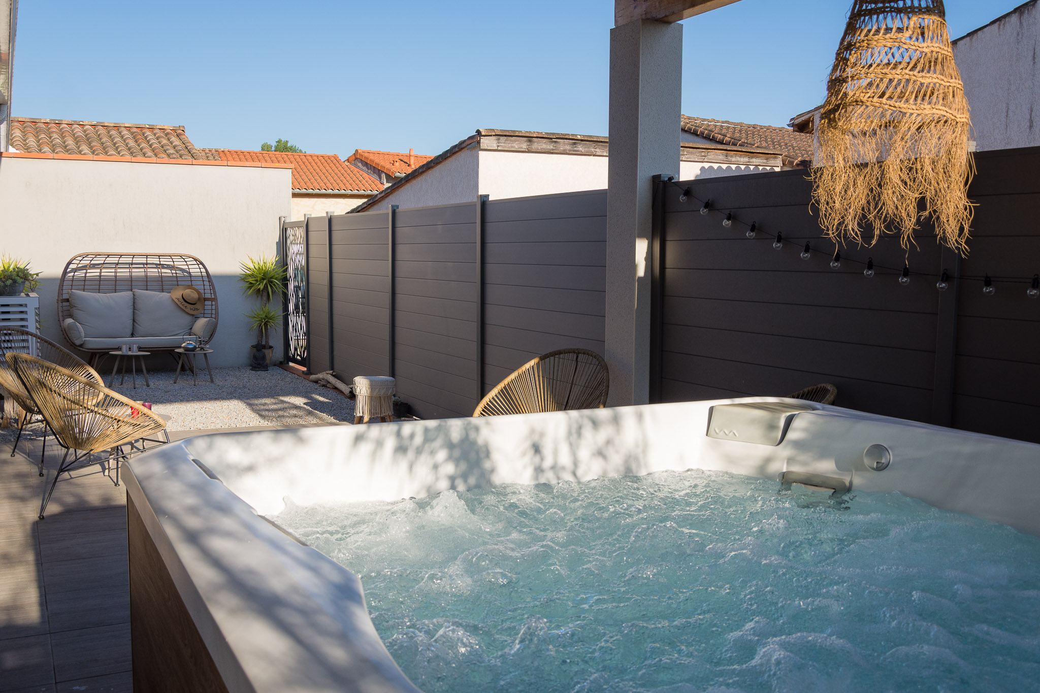 Terrasse avec jacuzzi privatif chez echapetvous à Tarbes, salon en rotin cosy et guirlande lumineuse